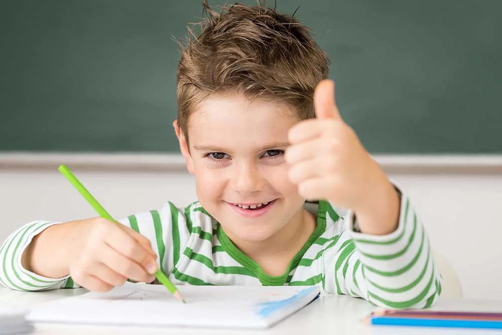 Grundschüler mit Stift zeigt den Daumen nach oben